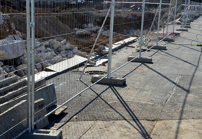 workers constructing a temporary fence with metal panels at a job site